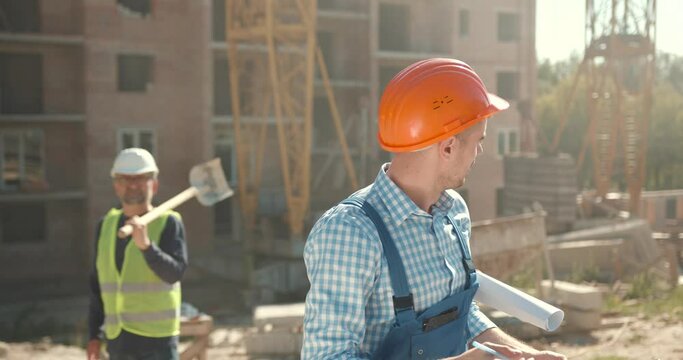 Superviser with blueprint standing at construction site