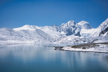 Fototapeta na wymiar Gurudongmar Lake with snow covered and beautiful lake view one of the best place to visit and enjoy during vacation. Snow capped mountains with breath taking view and is perfect for wallpaper