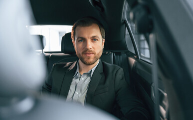 In comfortable modern automobile. Man in formal business clothes