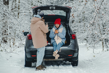 a man takes pictures of his beloved in a car in a snowy forest, they stopped to rest from the road