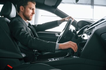 Obraz premium Man in formal business clothes is sitting in the modern automobile