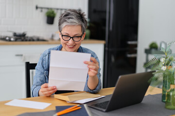 Smiling woman reading mail or bank account about money transfer.