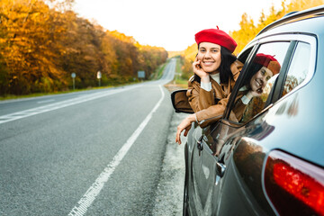 A woman peers out of the window of a car on the roadside in autumn
