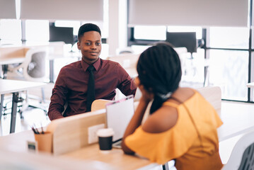 Fototapeta premium Two young african american business people working together in co-working space with happy together