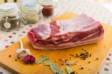 fresh piece of pork belly on wooden board with spices