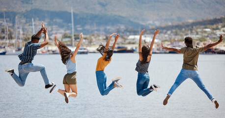 Friendship is arguably one of the most important aspects of life. Rearview shot of a group of friends jumping together on a pier.
