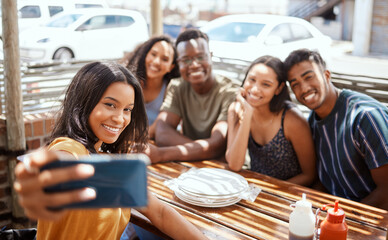 Feasting with the besties. Shot of a group of young friends taking selfies together at a restaurant.