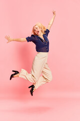 Portrait with one happy woman jumping with spreaded hands over pink studio background. Long awaited...