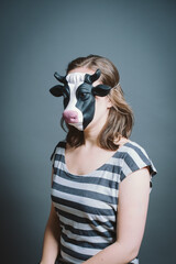 Young woman wearing mask against a grey background in studio. Young woman wearing mask against a grey background in studio.