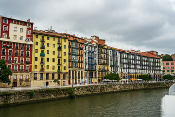 Fototapeta na wymiar Bilbao, Spain - 08.06.2022: Bright multi colored houses of the Nervion River. Colorful architecture, Bilbao, Spain.