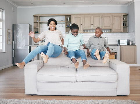 Rejoice With Your Family In The Beautiful Land Of Life. Shot Of A Family Jumping On To The Sofa At Home.