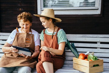 Grandmother and granddaughter watch something on a tablet together while relaxing after work on the...