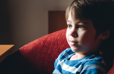 Beautiful brown eyes of 6 year boy looking at screen close-up. Smiling child is watching TV,...