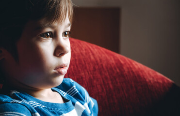 Beautiful brown eyes of 6 year boy looking at screen close-up. Child is watching TV, cartoons or...