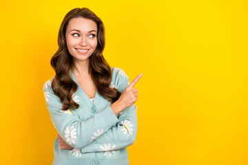 Photo of shiny dreamy lady dressed teal cardigan looking showing finger emtpy space isolated yellow color background