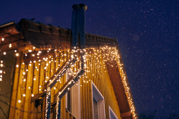 Christmas decorative yellow garlands lights fixed on house roof, outdoor evening Christmas home...
