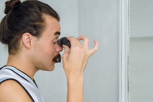 profile view of a non-binary gender person in her room putting makeup on her eyelids with a sponge