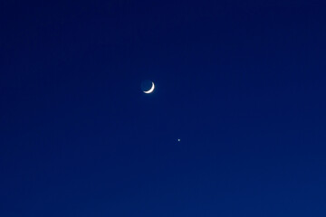 Obraz na płótnie Canvas Dark blue clear night sky with the moon and Venus. New growing moon.