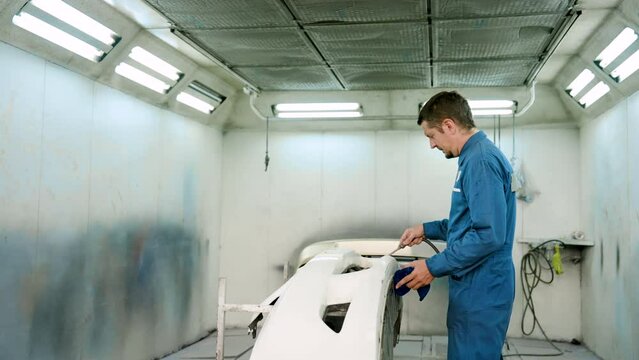 Slow motion, Male mechanic wearing molly clothes working in garage for work safety, uses dryer blow clean parts front car, which have been removed clean before applying new paint. in a car repair shop