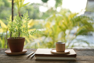 notebook and bamboo wooden coffee cup on wooden table with greenery scene