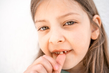 Charming smiling little girl kid with opened mouth shows staggering loose falling out first baby milk front tooth. Preschooler teeth changing. Healthy dental hygiene. Lost tooth. Dentist treatment