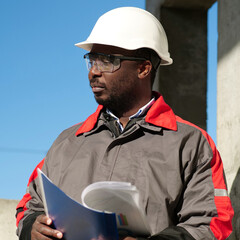 African american worker stands at construction site with work papers