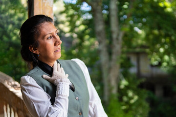 Profile portrait of a Latina woman dressed in traditional clothing, with a worried expression, her hand on her chest