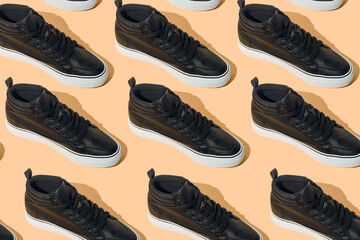 Shoe pattern. Black shoes on a beige pastel background top view with shadow. Accessories concept. New leather shoes. Classic sport style. Fashion shoe. Flat minimalistic store advertising. Footwear.