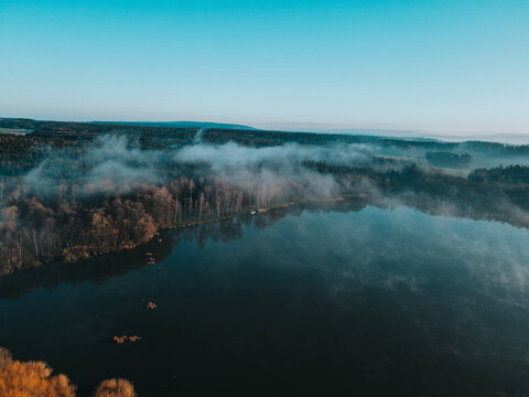 A foggy lake and forest during spring morning. Svitavy, Czechia.