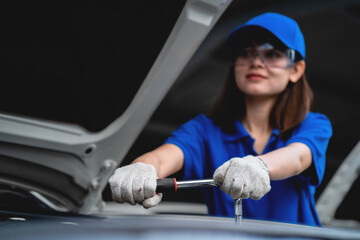 Professional Asian female mechanic inspects and repairs cars and maintains cars. Concept of car...
