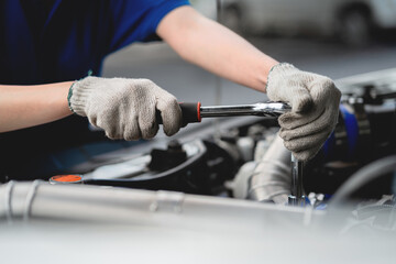 Close-up, a car mechanic checking the oil in a car's engine. Technician inspecting and maintaining the engine of a car or vehicle. Female car mechanic checking car engine