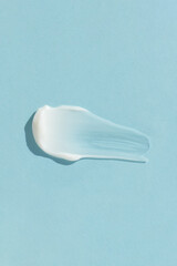 White cream texture on a blue background. A smear of a cosmetic skin care product. Wellness and...