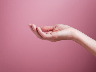 Main tendue de femme devant un fond rose. Isolé. Espace texte  - obrazy, fototapety, plakaty
