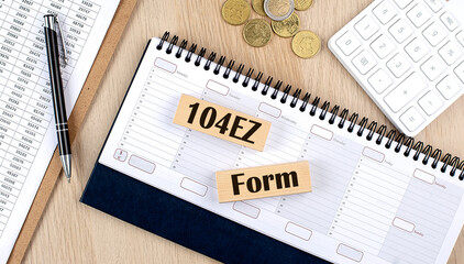 1040 EZ FORM word written on wooden block on planner with coins, clipboard and a calculator