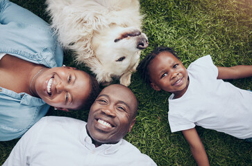 Our little family. Shot of a young family lying on the grass with their dog in their garden at home.