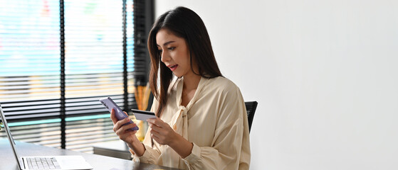 Portrait of Asian Business woman was surprised while using mobile phone and credit card, Free space...