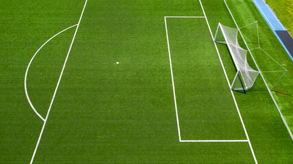 Aerial closeup of the penalty area on an empty synthetic grass soccer field. Here a penalty is taken in a soccer game.