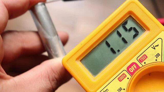 A man measures the pontential (Volts) of an empty  rechargeble AA batery using a multimeter