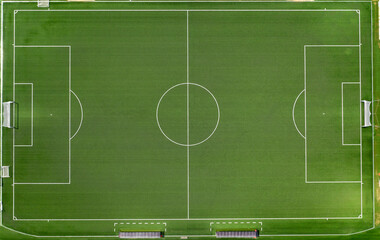 Perpendicular aerial view of an artificial turf soccer field. On the sidelines there are benches....