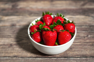 Fresh Bowl of strawberries on a wooden table.