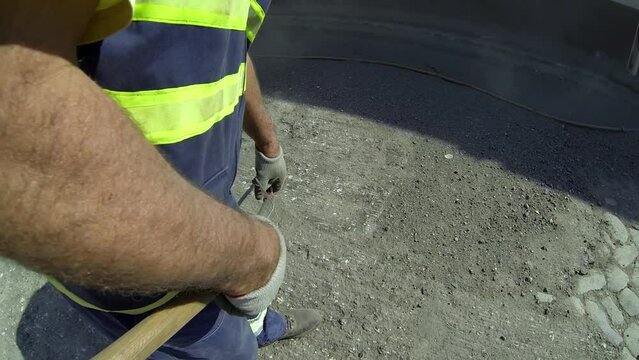 Road Worker Dressed in Reflective Clothing Cleaning Road with Compressed Air. Asphalt Pavement Removal. Maintenance and Road Repair. Road Construction Industry.