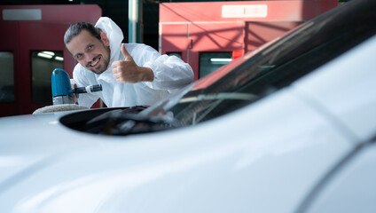 Auto mechanic use an electric polisher to polish the dried car paint. After passing the paint from the car painting room