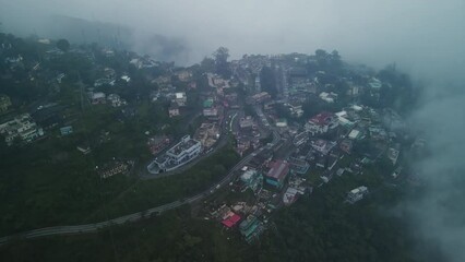 Aerial view of the town in the mountain, Narendranagar, Tehri Garhwal, Uttarakhand, India. Hilly road in India on a foggy day. Transportation on a hilly Indian road during monsoon. 