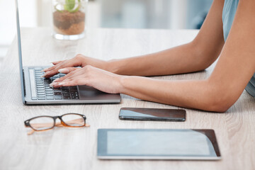 Closeup of mixed race business womans hands and fingers typing on laptop keyboard at a table in an office. One female only sending emails while busy with research and planning online for her startup