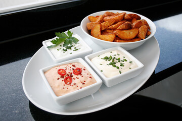 Kartoffelecken mit Saucen auf Teller angerichtet mit Sauce und Sour Creme