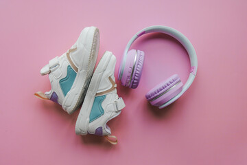 White children's sneakers and headphones on a pink background with copy space. Banner