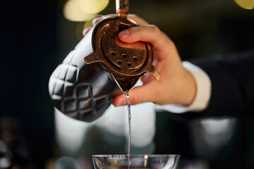 The bartender pours a cocktail from a shaker into a glass. Luxury hotel bar
