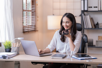 Young happy businesswoman working with tablet and mobile phone in corporate office.