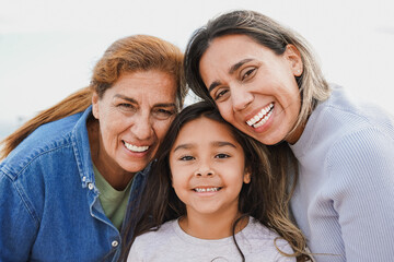 Portrait of happy latin multigenerational family smiling on camera - Grandmother, mother and child...