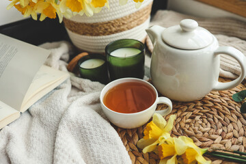 Cup of tea, candles, basket with daffodils, spring aesthetic photo